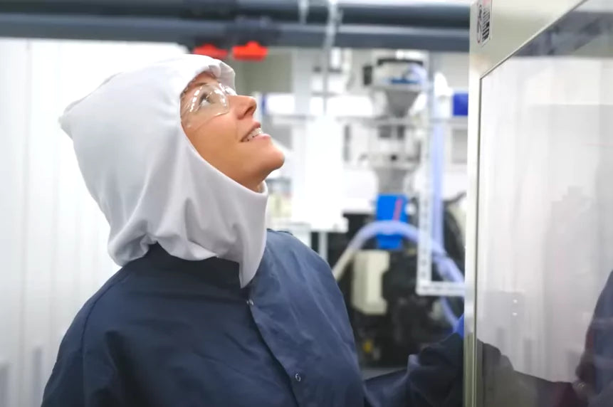 Person in cleanroom suit inspecting equipment in a manufacturing facility