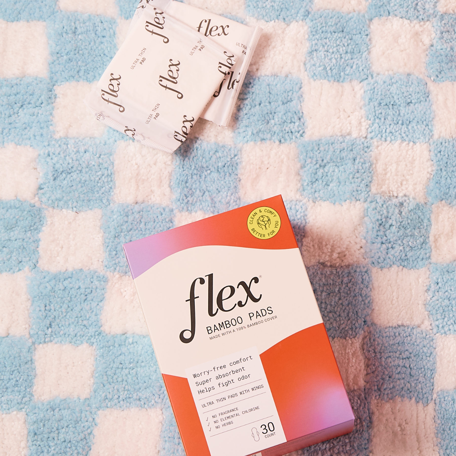 Box of Flex bamboo pads with two individually wrapped pads on a checkered surface