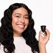 A person smiling and showing a Flex Menstrual Cup