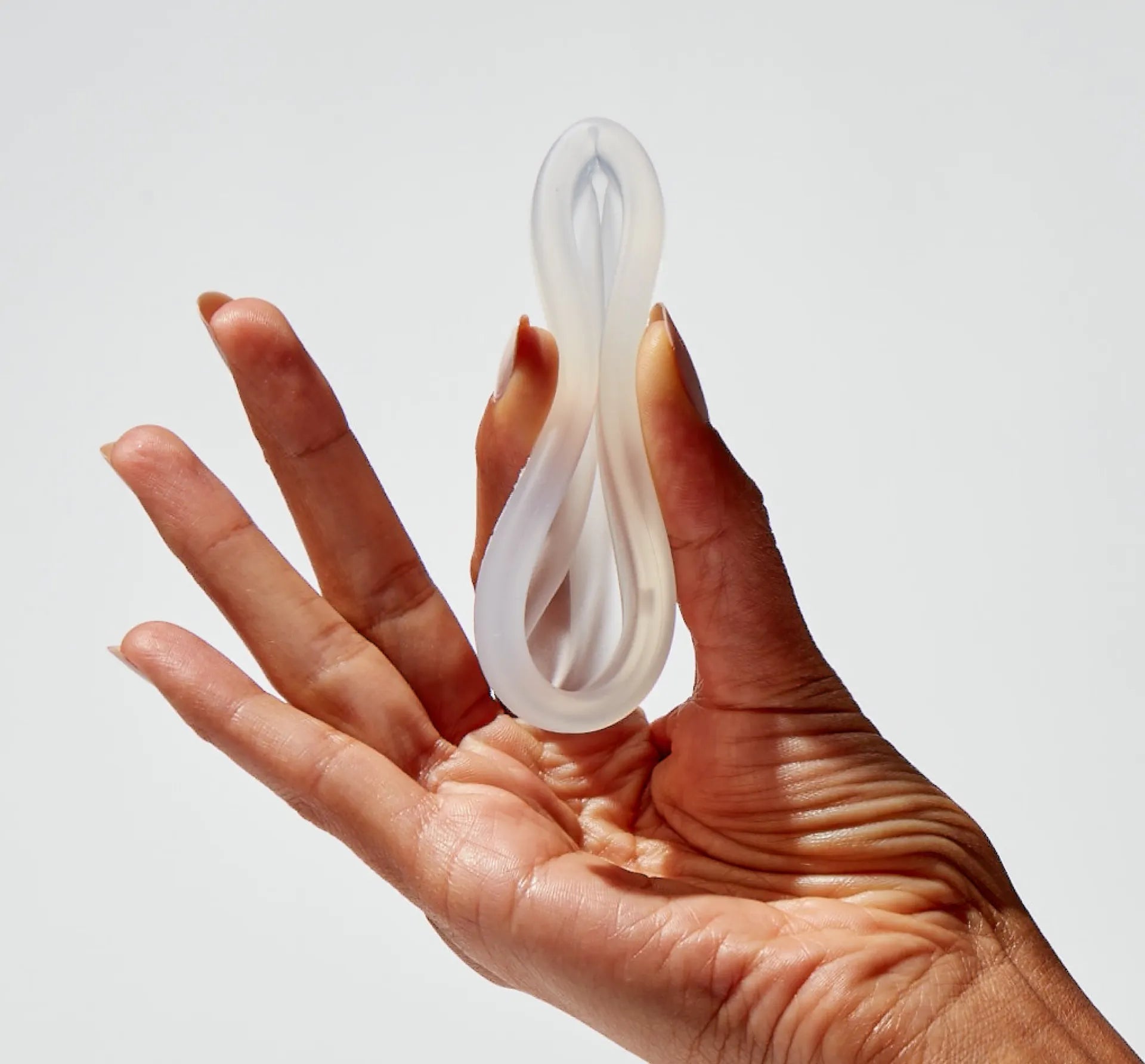 Person pinching a flex reusable menstrual disc by the middle to show size and insertion technique