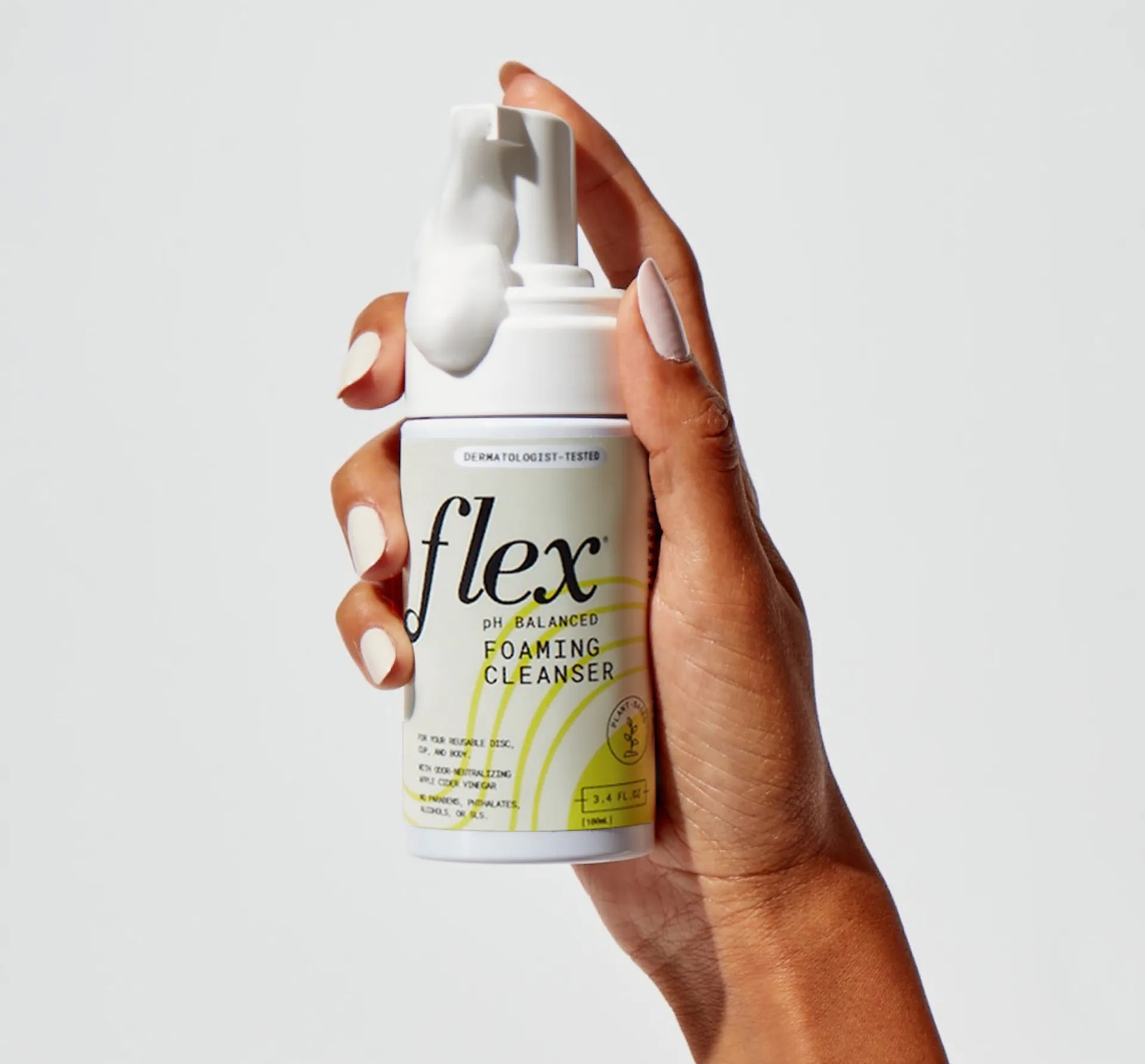 Hand holding foaming feminine cleanser bottle with foam dispensed from pump