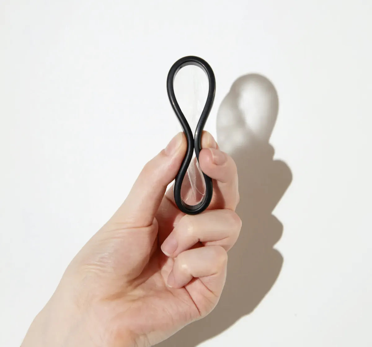 Hand holding a flexible menstrual disc pinched into figure-eight shape