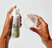 A person holding a flex reusable menstrual disc and a foaming cleanser
