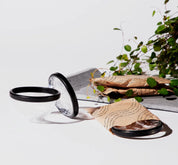 Three menstrual discs shown, one partially packaged and two unwrapped on a white surface with paper wrappers nearby.