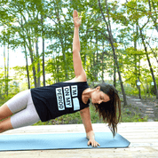 Person doing side plank on yoga mat wearing shirt with period-related text