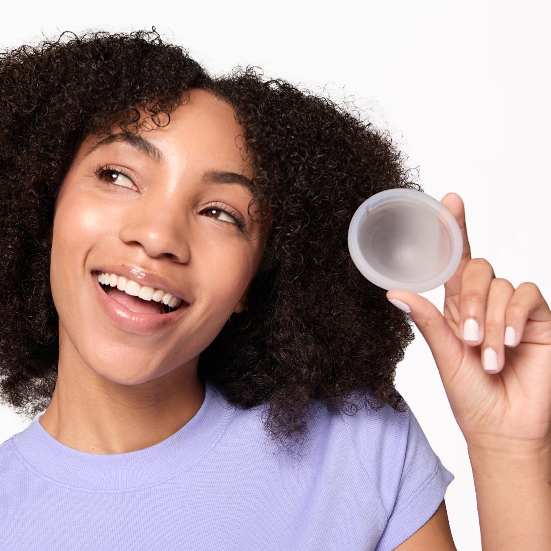 Person holding a reusable menstrual disc near face, showing size and shape